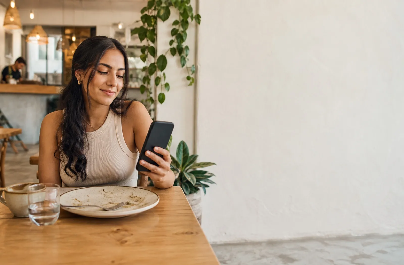 Clienta consultando beneficios desde su teléfono en una cafetería